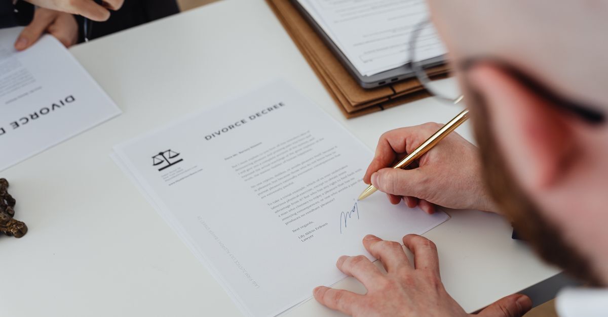 Crimes em licitacoes e contratos inline 1 525444 1785672722 Pessoa assinando documentos em uma mesa, indicando envolvimento em um processo legal.