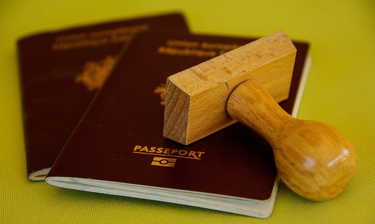 Passaportes e um estampador de madeira sobre uma superfície amarela.