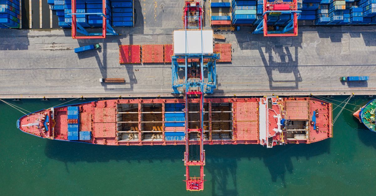 Carga de contêineres sendo descarregada de um navio em um porto.