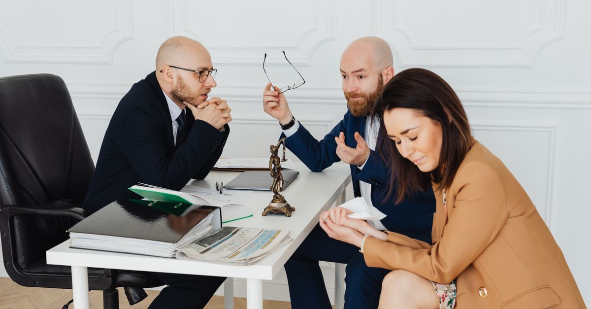 Divorcio inline 2 86099 1786095321 Duas pessoas sentadas em frente a uma mesa discutindo, uma com óculos na mão e a outra com um documento, em um ambiente de escritório.