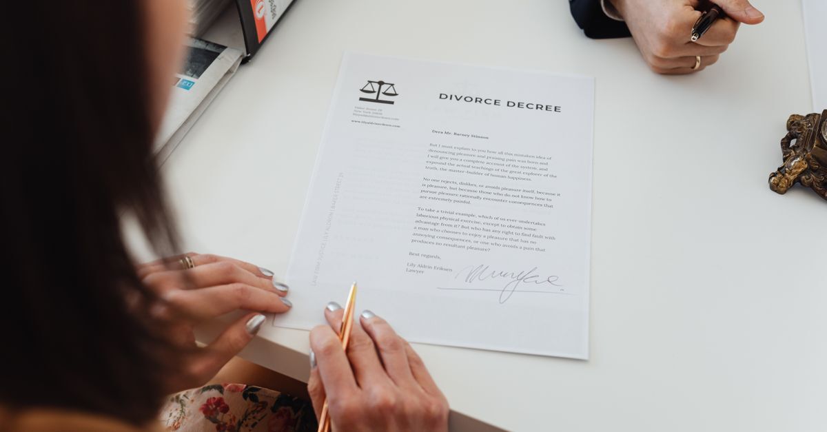 Divorcio inline 2 88197 1786534530 Mulher assinando um documento de divórcio em uma mesa, com outra pessoa ao lado.
