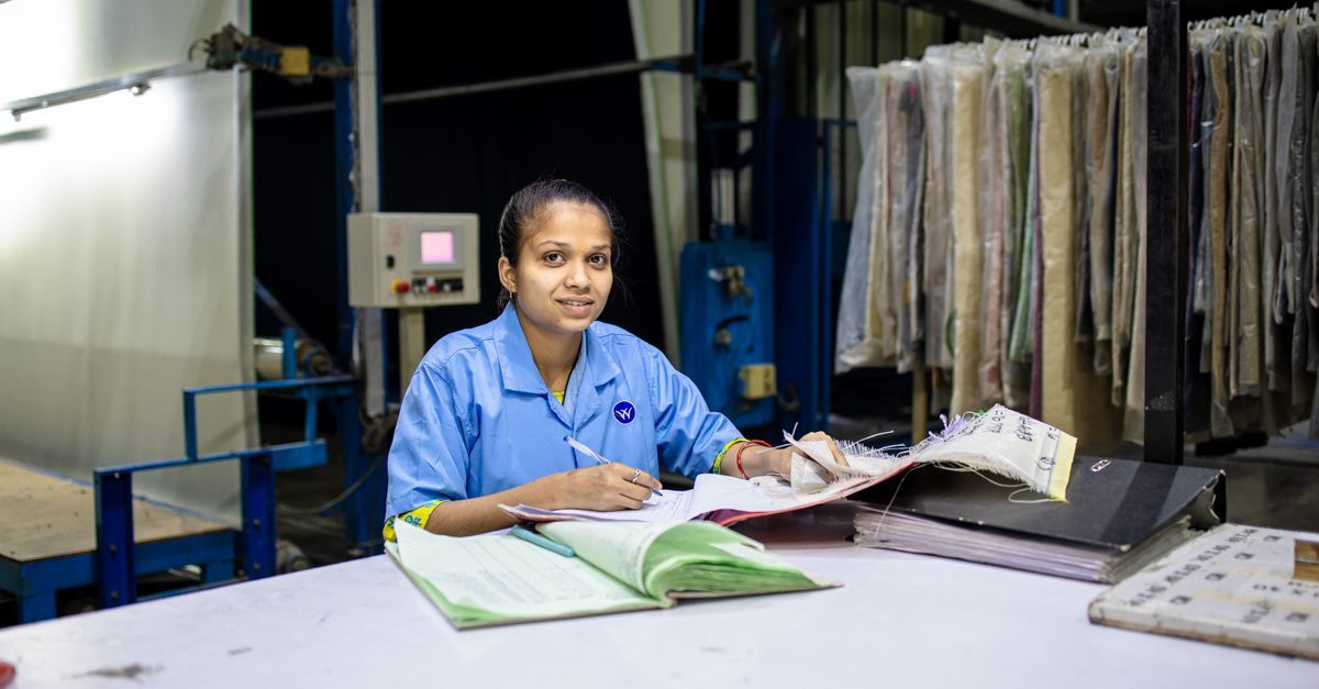 Mulher em ambiente de trabalho, sentada em uma mesa com documentos e materiais de escritório.