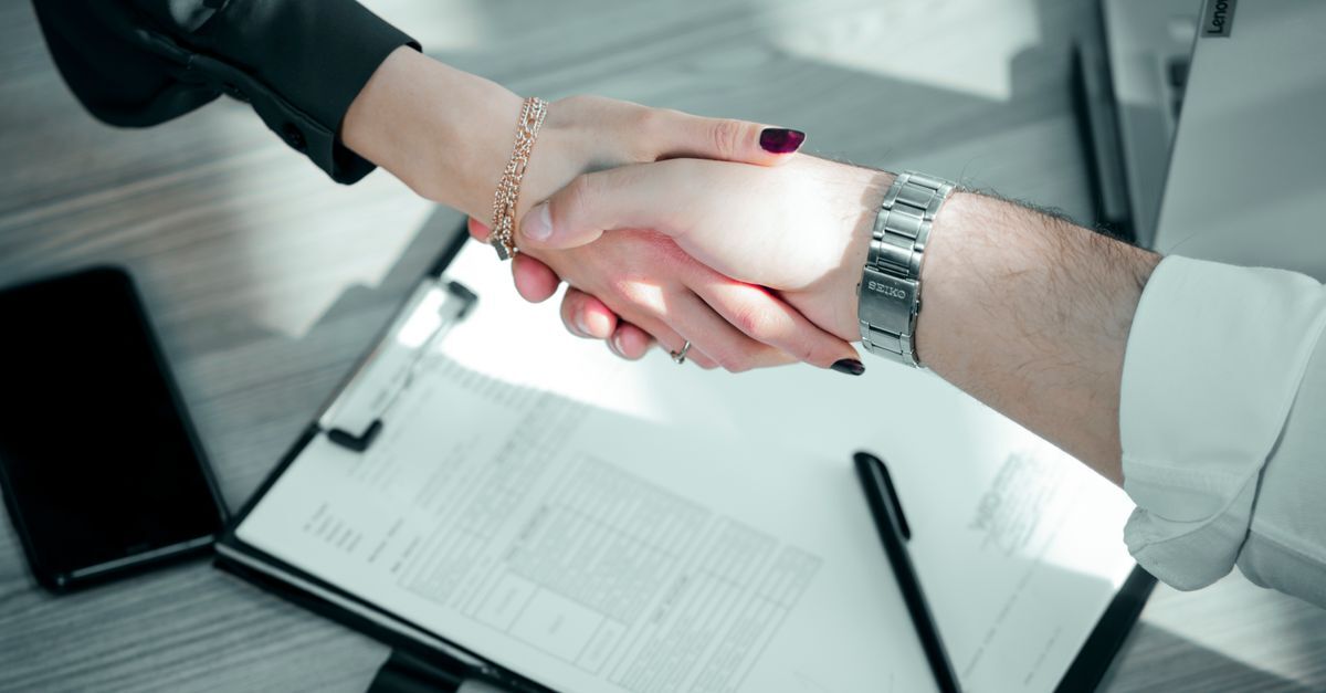 International arbitration in brazil inline 1 617837 1786725322 Duas pessoas de mãos dadas sobre documentos, sugerindo acordo legal ou comercial.