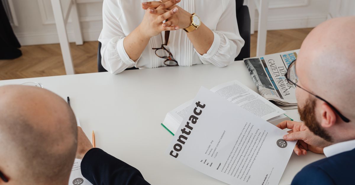 Duas pessoas analisando um contrato em uma mesa.