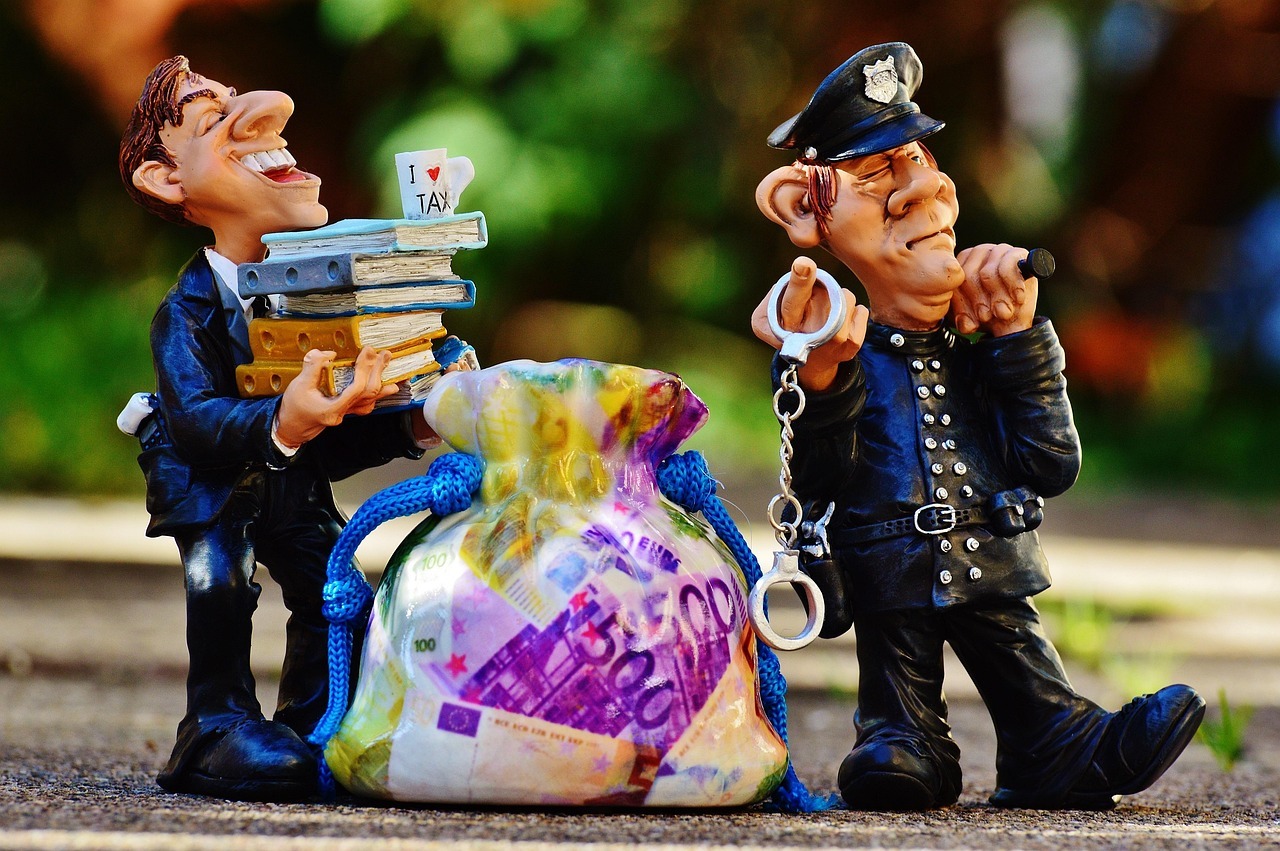 Inventario e partilha inline 2 369997 1786181776 Duas figuras caricaturas com dinheiro e documentos, uma segurando uma bolsa de dinheiro e a outra com algemas.
