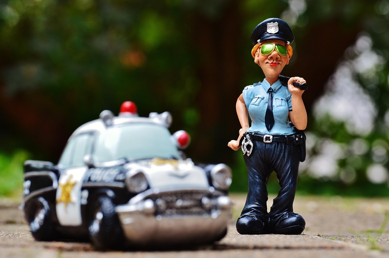 Lei maria da penha inline 2 403695 1786563303 Estátua de um policial com capacete e cinto de utilidades ao lado de um carro policial.