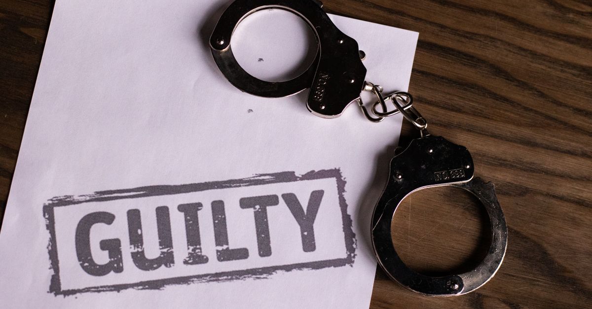 Aleguas sobre um papel com a palavra 'guilty' estampada, sobre uma superfície de madeira.