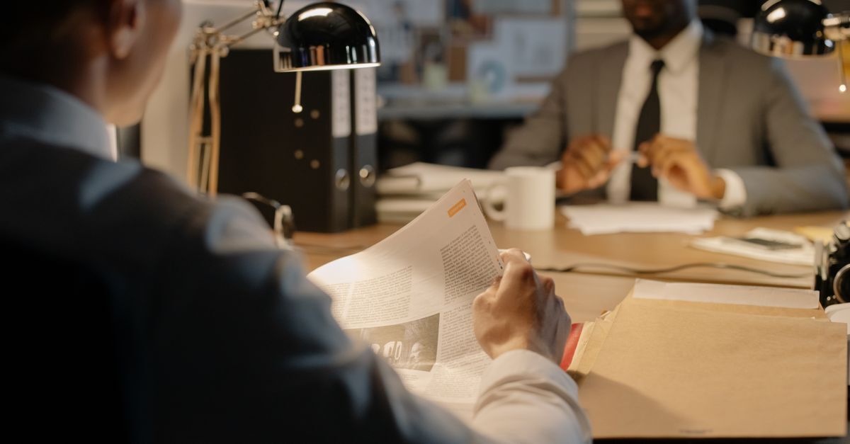 Piramides e fraude em investimentos inline 1 539237 1785845150 Duas pessoas em uma mesa discutindo documentos em um ambiente de escritório.