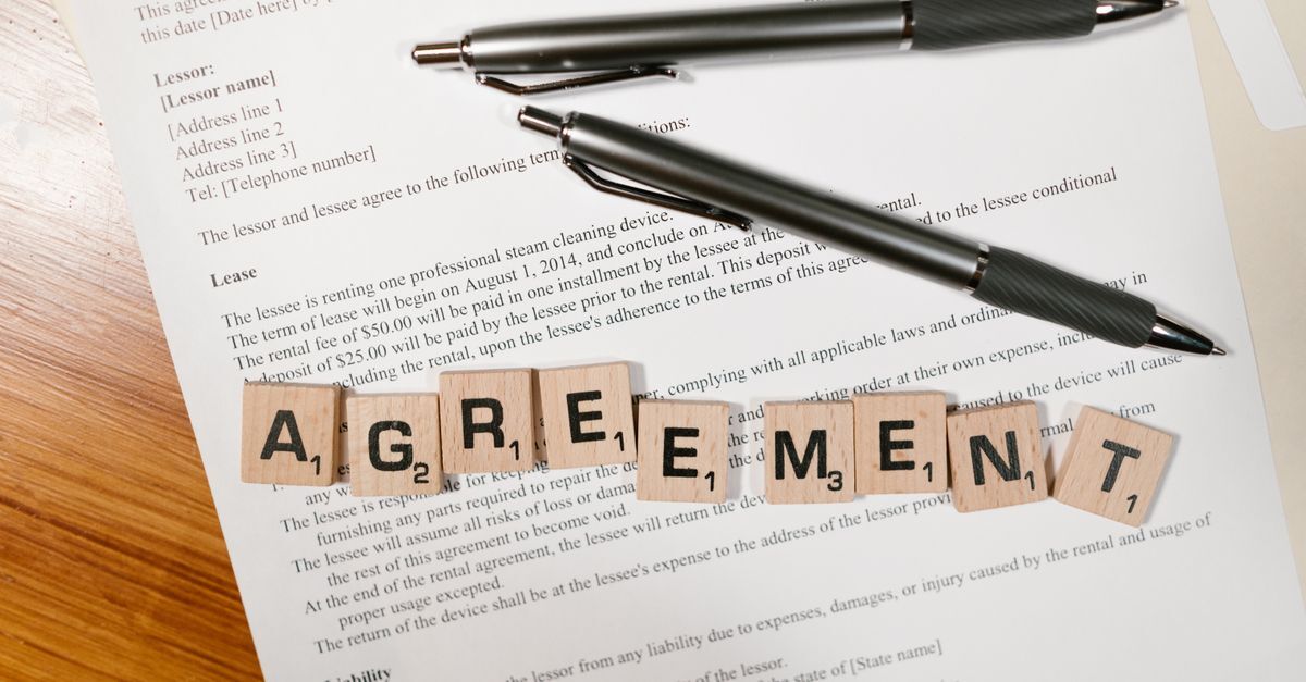 Renting property in brazil as a foreigner inline 1 585167 1786379697 Papel com texto e duas canetas sobre uma mesa, com blocos de letras formando a palavra 'agreement'.
