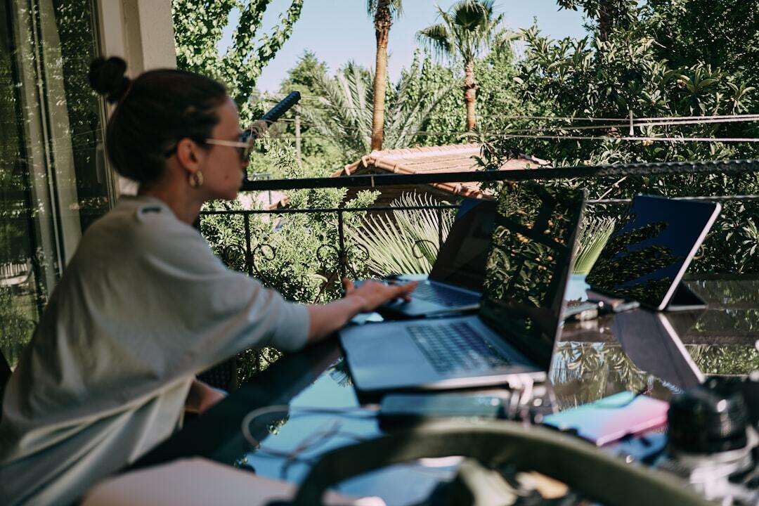 Residency visa in brazil inline 2 123325 1786887243 Mulher trabalhando em laptops em um espaço externo com vista para árvores.