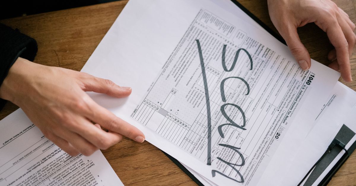 Sonegacao fiscal e crimes tributarios inline 2 651762 1787141081 Pessoa marcando um documento como 'scam' em uma mesa.